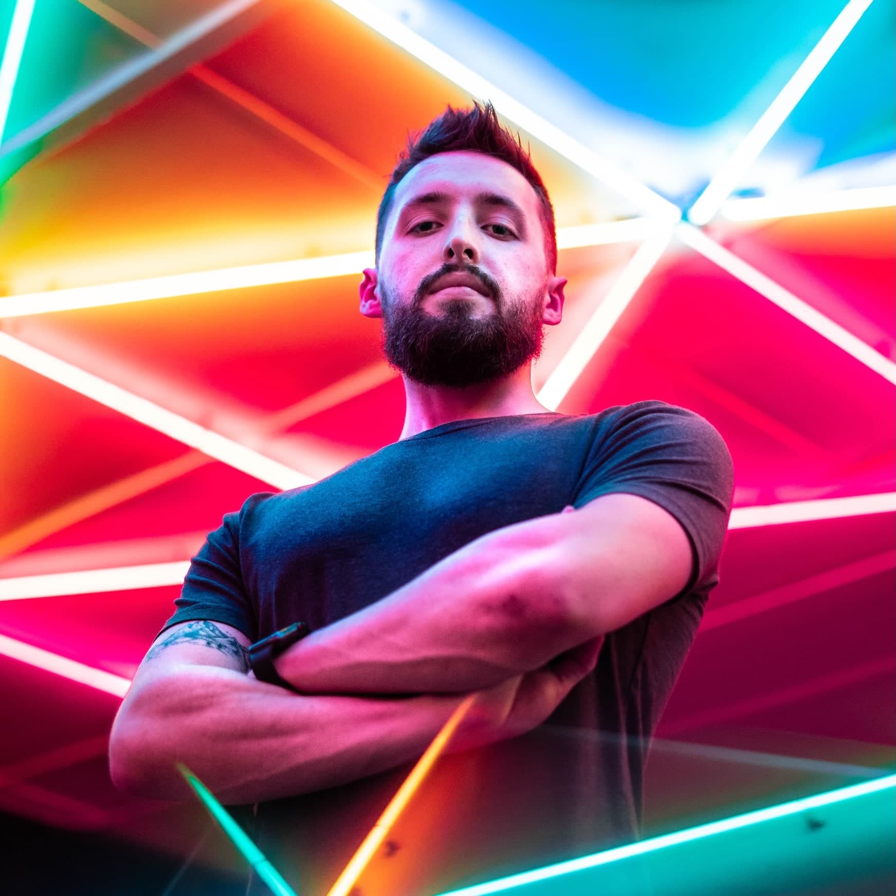 Photo of Max McKinney, behind a neon sign, looking at the camera